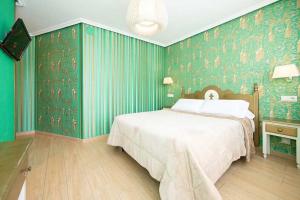 a bedroom with a large bed and green wallpaper at Alojamiento Playa de Candás in Candás