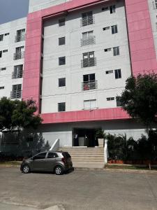 a car parked in front of a pink and white building at Apartamento Cerca al Rio y Complejo Deportivo in Valledupar