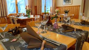 una sala da pranzo con tavolo e bicchieri da vino di Gasthaus Alpenrose a Innerferrera