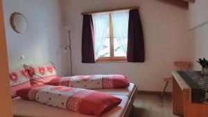 two beds in a room with a window at Gasthaus Alpenrose in Innerferrera