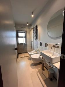 a bathroom with two toilets and a sink and a mirror at Hotel Lachea in Acitrezza
