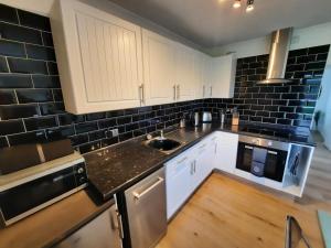 a kitchen with white cabinets and black brick walls at 2 Bed Chalet St Margaret's at Cliffe South Coast in Dover