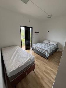 two twin beds in a room with wooden floors at Apartamento cobertura duplex Ubatuba - Praias Tenório e Grande in Ubatuba