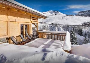 une cabane en rondins avec de la neige sur le porche dans l'établissement Chalet Macaron - Les Congères, au Grand-Bornand