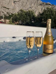 a bottle of champagne and two wine glasses on a table at Apartman Koko with private jacuzzi in Makarska
