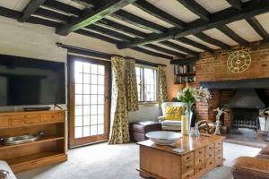 a living room with a large television and a brick wall at Sea Breeze in South Hayling