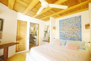 a bedroom with a white bed with a painting on the wall at Havre de paix, 2 pas de la plage in Las Terrenas