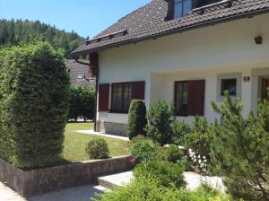 a white house with trees and bushes at Apartment Tanja in Kranjska Gora