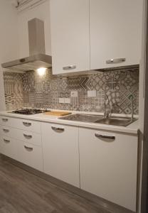 una cocina con armarios blancos y fregadero en Corso Italia, en San Giovanni Valdarno