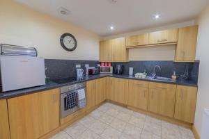 a kitchen with wooden cabinets and a clock on the wall at Quay Head View Aparthotel in Stranraer