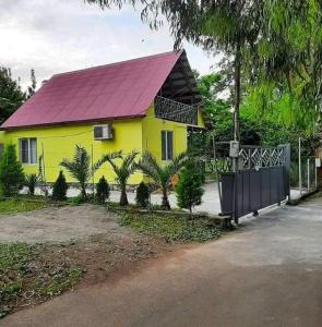 a yellow house with a red roof and palm trees at Yellow chalet 021. in Batumi