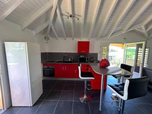 a kitchen with red cabinets and a table with chairs at Logement Ghenoah in Petit-Canal