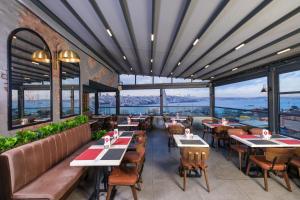 un restaurante con mesas, sillas y ventanas grandes en Glamour Hotel Istanbul Sirkeci, en Estambul