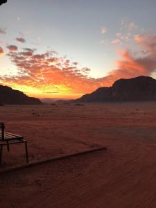 einen Sonnenuntergang in der Wüste mit einer Bank im Vordergrund in der Unterkunft Alarb Quiet Camp in Wadi Rum