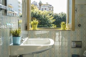 un bagno con lavandino e finestra con piante in vaso di Casa della Villa Pozzallo a Pozzallo