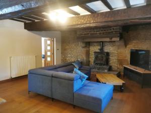 sala de estar con sofá azul y chimenea en La Bureliere- Holiday home for families, groups and couples, en Gorron
