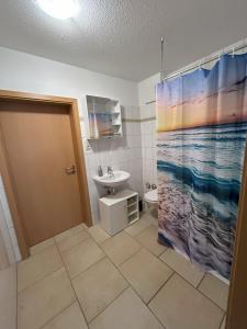 uma casa de banho com um lavatório e uma cortina de chuveiro em Ferienwohnung am Ostseeküstenradweg em Stralsund