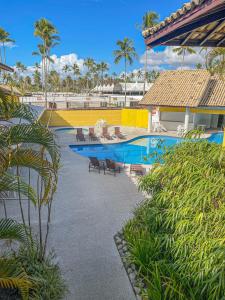 a resort with a pool and chairs and palm trees at Sunshine Praia Hotel in Porto Seguro