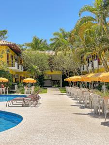 una fila de sillas y sombrillas junto a una piscina en Sunshine Praia Hotel, en Porto Seguro