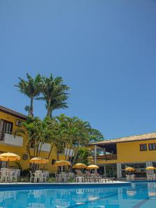 um hotel com uma piscina com guarda-sóis e cadeiras em Sunshine Praia Hotel em Porto Seguro