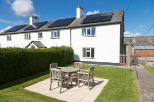 a table and chairs in front of a white house at Granary at Tyddyn Isaf in Ruthin