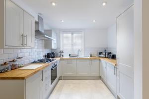 a kitchen with white cabinets and wooden counter tops at Luxury 5 Bedroom House By The Sea in Brighton & Hove