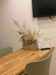 - une table en bois avec un vase et une télévision sur le dessus dans l'établissement LA MAISON D’ANTOINE 1, à Chamalières