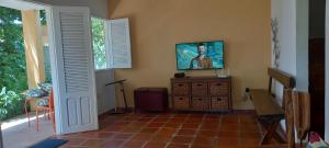 ein Wohnzimmer mit einem TV und Fliesenboden in der Unterkunft O melhor lugar pra família, em Tamandaré in Tamandaré