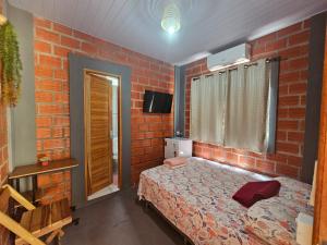a bedroom with a red brick wall and a bed at Pousada Vipayu perto da Orla de Alter a apenas 50 metros da praia in Alter do Chao