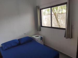 ein Schlafzimmer mit einem blauen Bett und einem Fenster in der Unterkunft Casa Cardoso in Bertioga