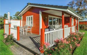 ein kleines orangefarbenes Haus mit einer Terrasse mit einem Tisch in der Unterkunft 2 Bedroom Pet Friendly Home In Sydals in Skovby