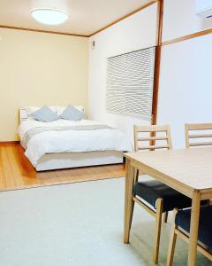 1 dormitorio con 1 cama, mesa y sillas en 日田ホステル　Hita Hostel en Hita