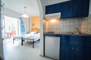 a kitchen with blue cabinets and a living room at Studios Stratos in Naxos Chora