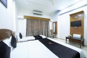a hotel room with a bed and a tv at Saish Hotel Shirdi in Shirdi
