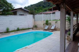 einen Pool mit zwei Stühlen neben einem Haus in der Unterkunft Chacára Familia Buscapé Oliveira in Araçariguama