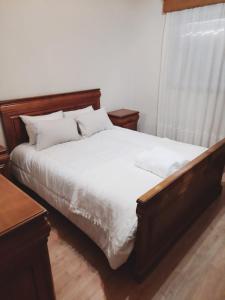 uma cama com lençóis brancos e almofadas num quarto em Casa da Carlota em Cinfães