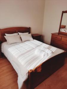 uma cama grande com lençóis brancos e uma cómoda em Casa da Carlota em Cinfães