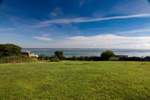 un campo de hierba verde con el océano en el fondo en Fort Victoria Cottages - Spinnakers, en Yarmouth