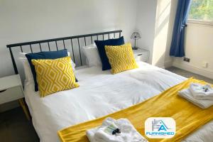 a bedroom with a bed with yellow and blue pillows at Penthouse - Central - Parking in Harrogate