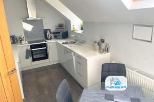 a small white kitchen with a table and a chair at Penthouse - Central - Parking in Harrogate