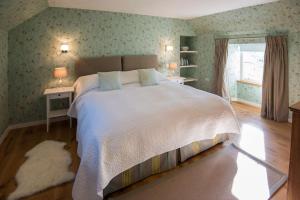 een slaapkamer met een groot bed en een raam bij Keeper's Cottage, Straloch Estate in Perth