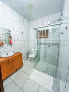 uma casa de banho com uma cabina de duche em vidro e um WC. em Ótima casa no centro de Carrancas em Carrancas