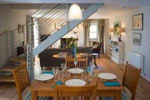 a dining room and living room with a table and a staircase at Keeper's Cottage, Straloch Estate in Perth