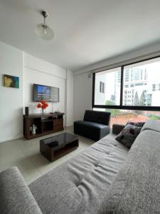 a living room with a couch and a tv at ¡ACOGEDOR DEPTO. DE 2 DORMITORIOS CON PISCINA! in Santa Cruz de la Sierra