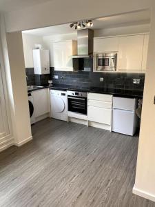 a large kitchen with white cabinets and appliances at National Arena, free Parking in Nottingham