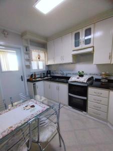 a kitchen with white cabinets and a black stove top oven at Apto aconchegante ao lado da Vinícola Garibaldi in Garibaldi