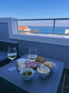 una mesa con copas de vino y comida en el balcón en Couples Cove: Luxe Getaway w/ jetted bath & views, en Ciudad del Cabo