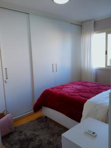 een slaapkamer met een bed met een rode deken bij Apto aconchegante ao lado da Vinícola Garibaldi in Garibaldi
