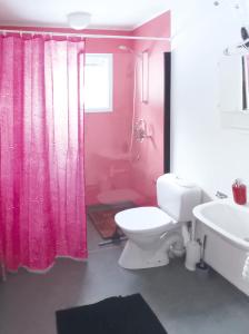 La salle de bains est pourvue d'un rideau de douche rose et de toilettes. dans l'établissement Fritidshus - Cottage - Holiday house - Soluppgång, à Blattniksele