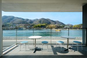 a balcony with two tables and chairs and a view of the water at BONAPOOL in Onomichi